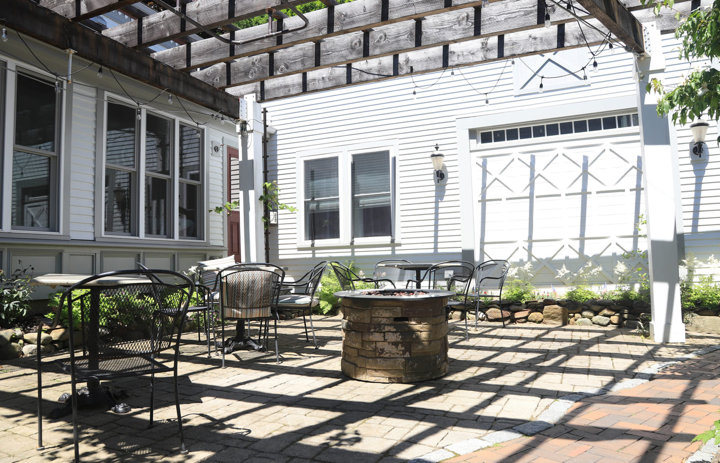 The pergola courtyard with bistro tables, string lights and a fire pit