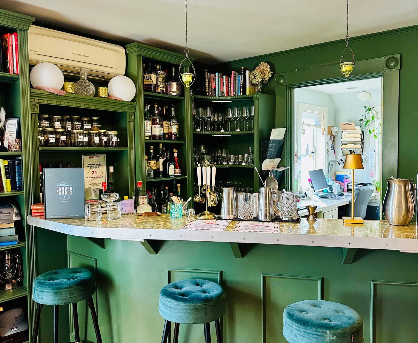 The green-panelled bar with teal velvet stools and cocktail glassware