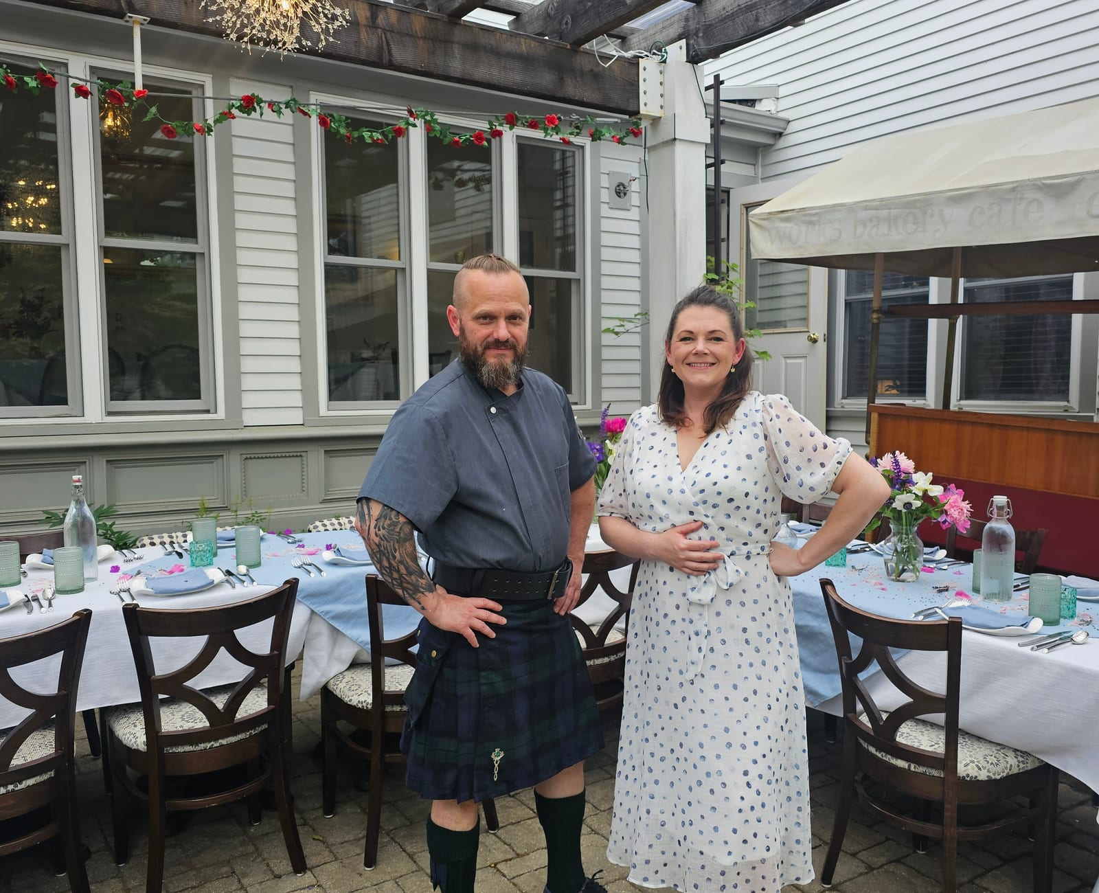 Two long banquet tables set for about fourteen under the courtyard pergola, with Chef Tom E. White