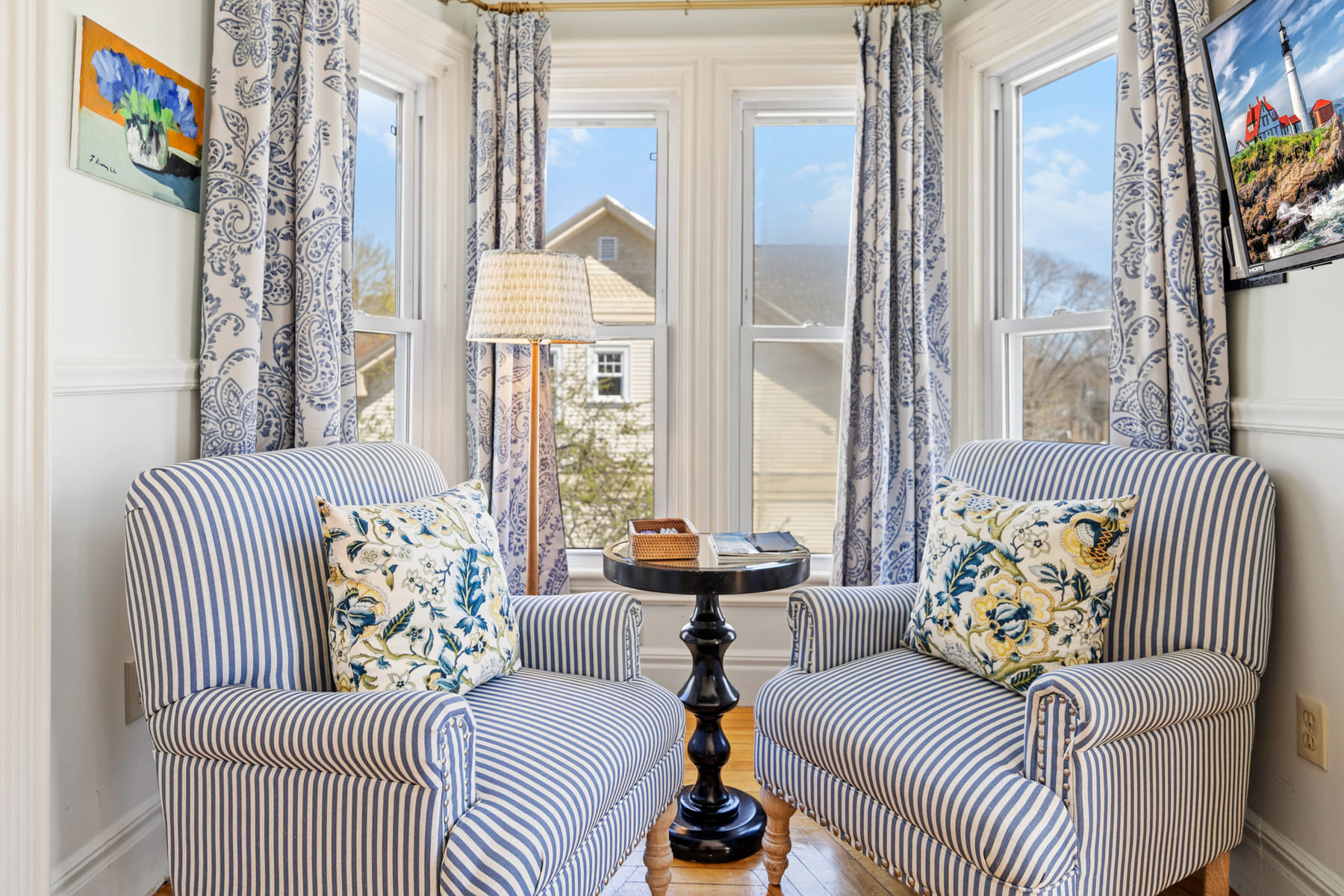 Two striped armchairs facing each other in a sunlit bay window
